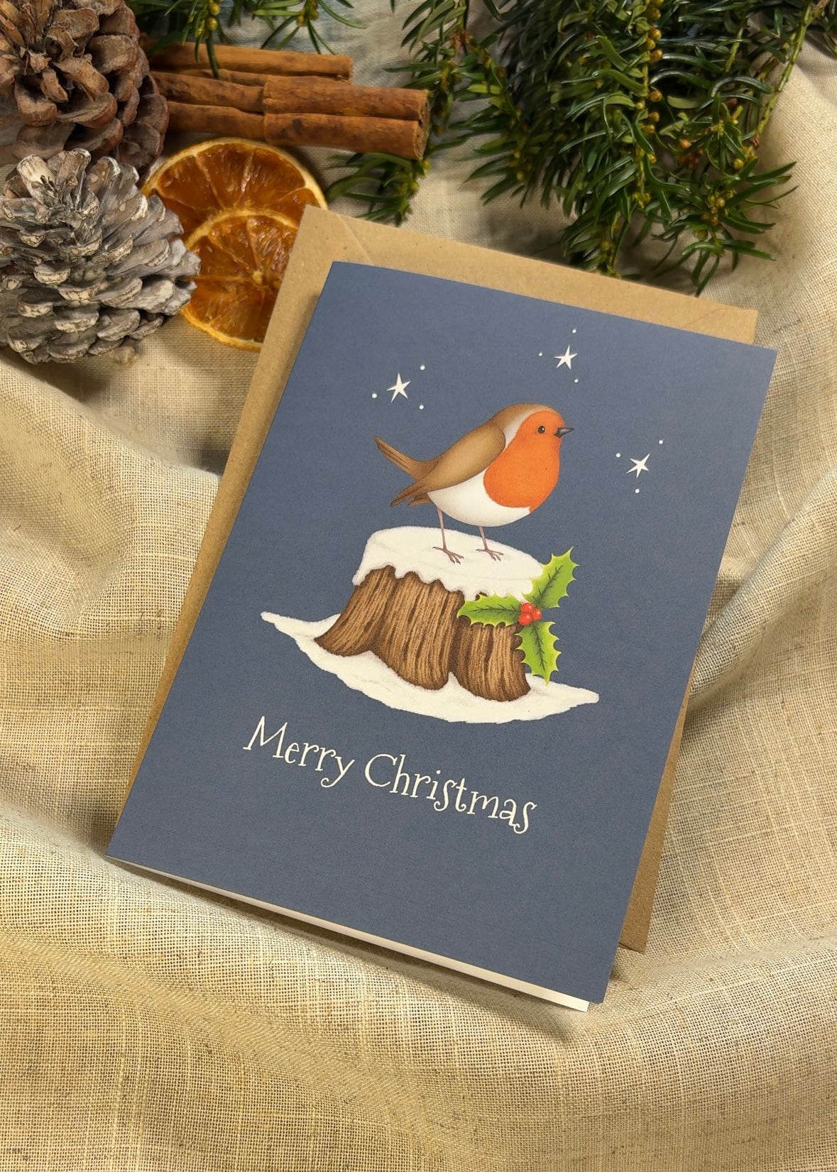 Christmas card with a robin on a holly stump illustration, surrounded by festive decorations.